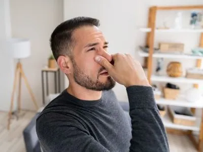 man holding his nose because of a musty odor