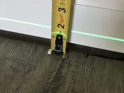 Measuring tape measuring wall and floor gap.